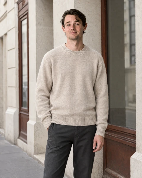 Man wearing an ivory crewneck sweater outside a stone building.